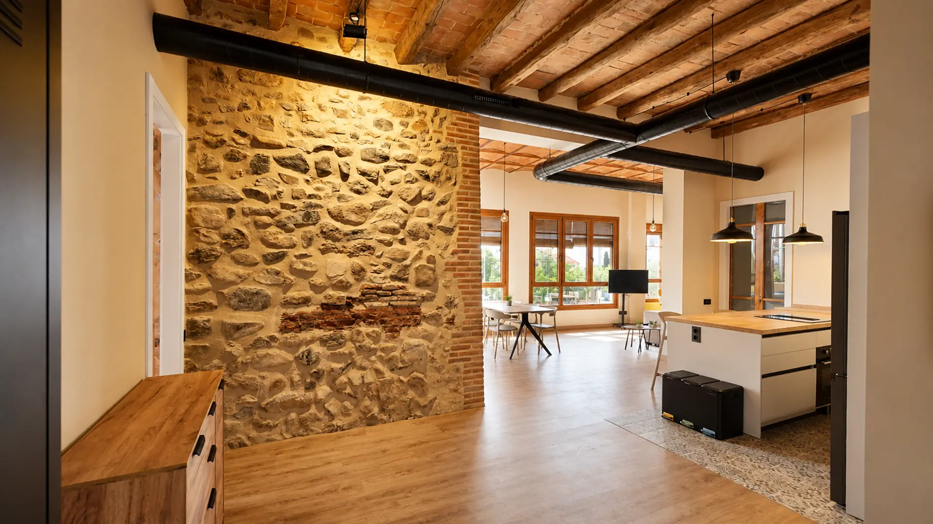 Interior de l'apartament Avellana Pauetet amb paret de pedra i cuina oberta